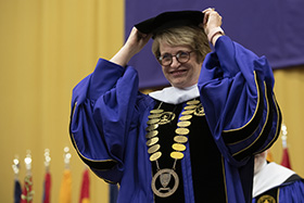 Saint Michael's College's 17th President Dr. D. E. Lorraine Sterritt, center, sits with her two predecessors, Jack Neuhauser, left, and Marc vanderHeyden, on either side in the large photo above the headline; directly above, she smiles topping off the full regalia of the president; below, Sterritt delivers her Inaugural address; students process with banners across the green to the ceremony; in the Chapel with her family members during the pre-Inauguration prayer service; and striding forward across campus en route to her new responsibilities. (photos by Jerry Swope)