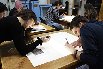Students working in their Sloane classroom at light tables on their individual drawings.