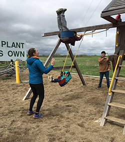 students pushing child on swings