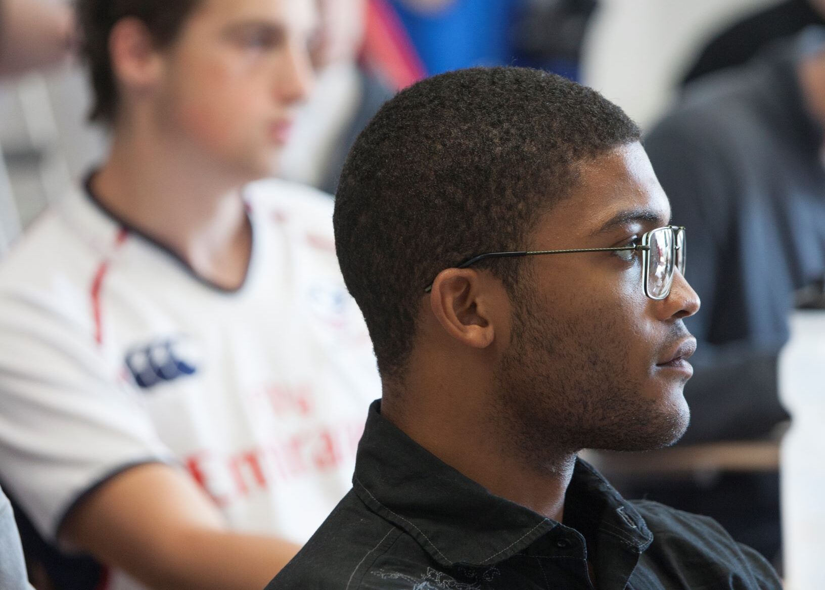 close up of a male student listening in class with classmates int eh background