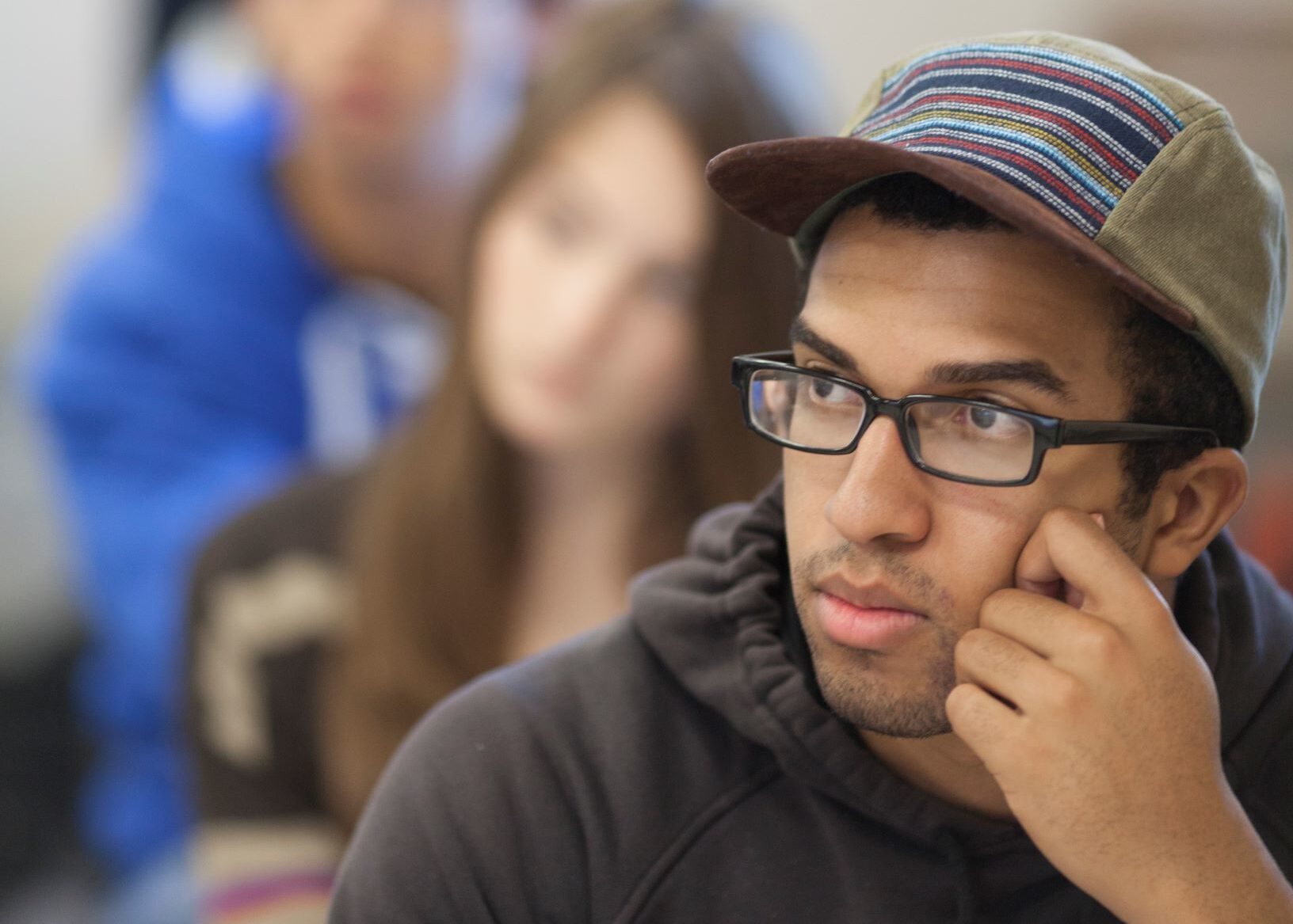 Student listening in class, with people out of focus listening behind him.