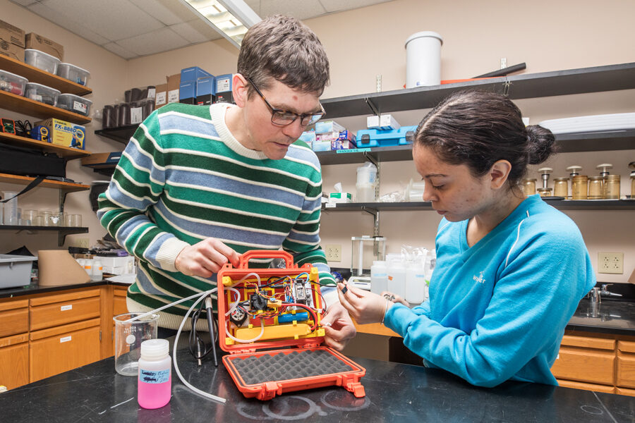 Assistant Professor Clay Williams working on experiement in a lab with a student.