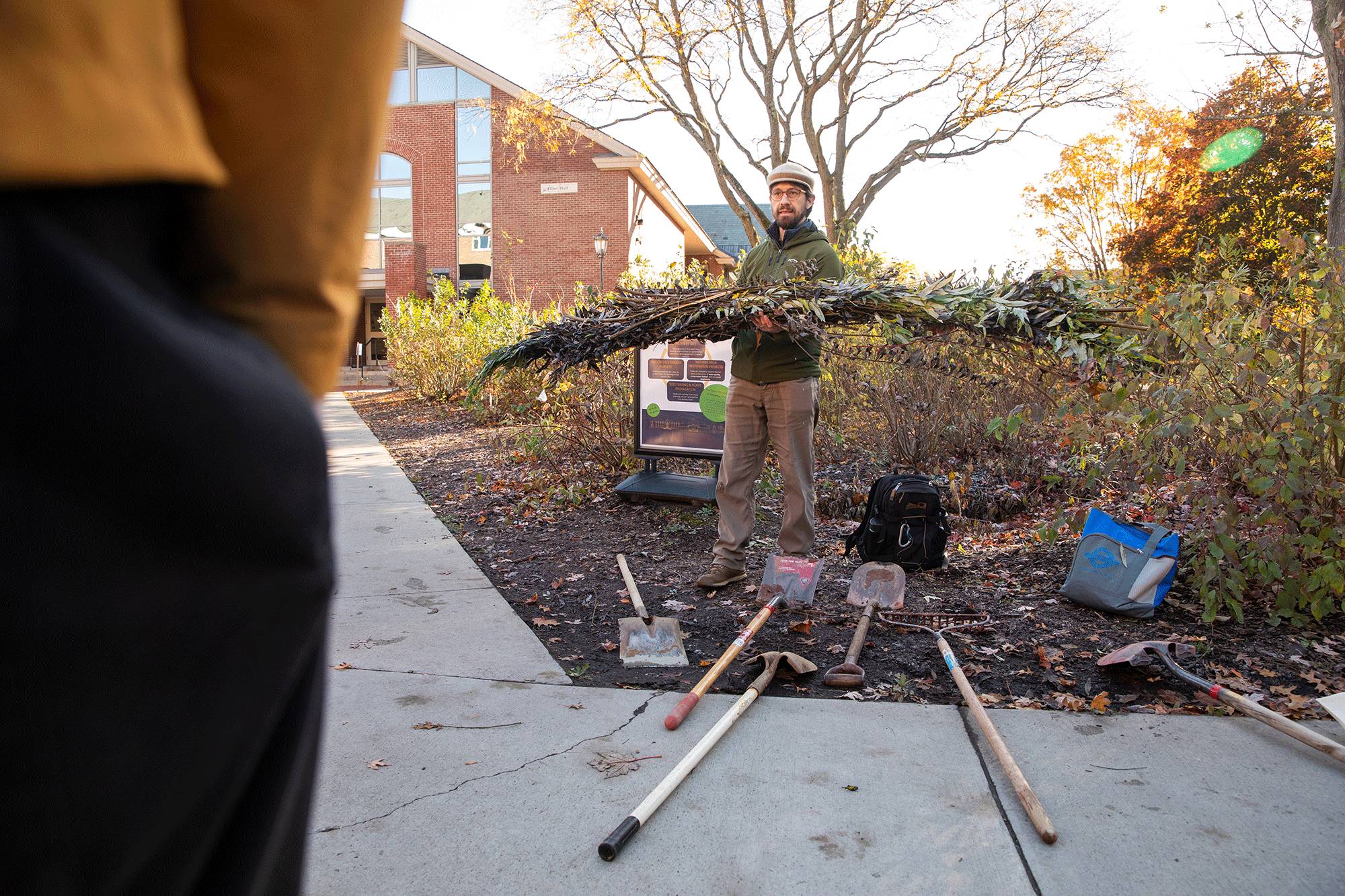 Professor Trevian Stenger speaks to a group of students in front of the tree nursery on the campus of Saint Michael's College.