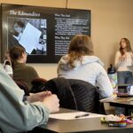 student presenting on the edmundites as others watch and listen