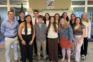 group of students posing for a picture in front of a fireplace in pomerleau
