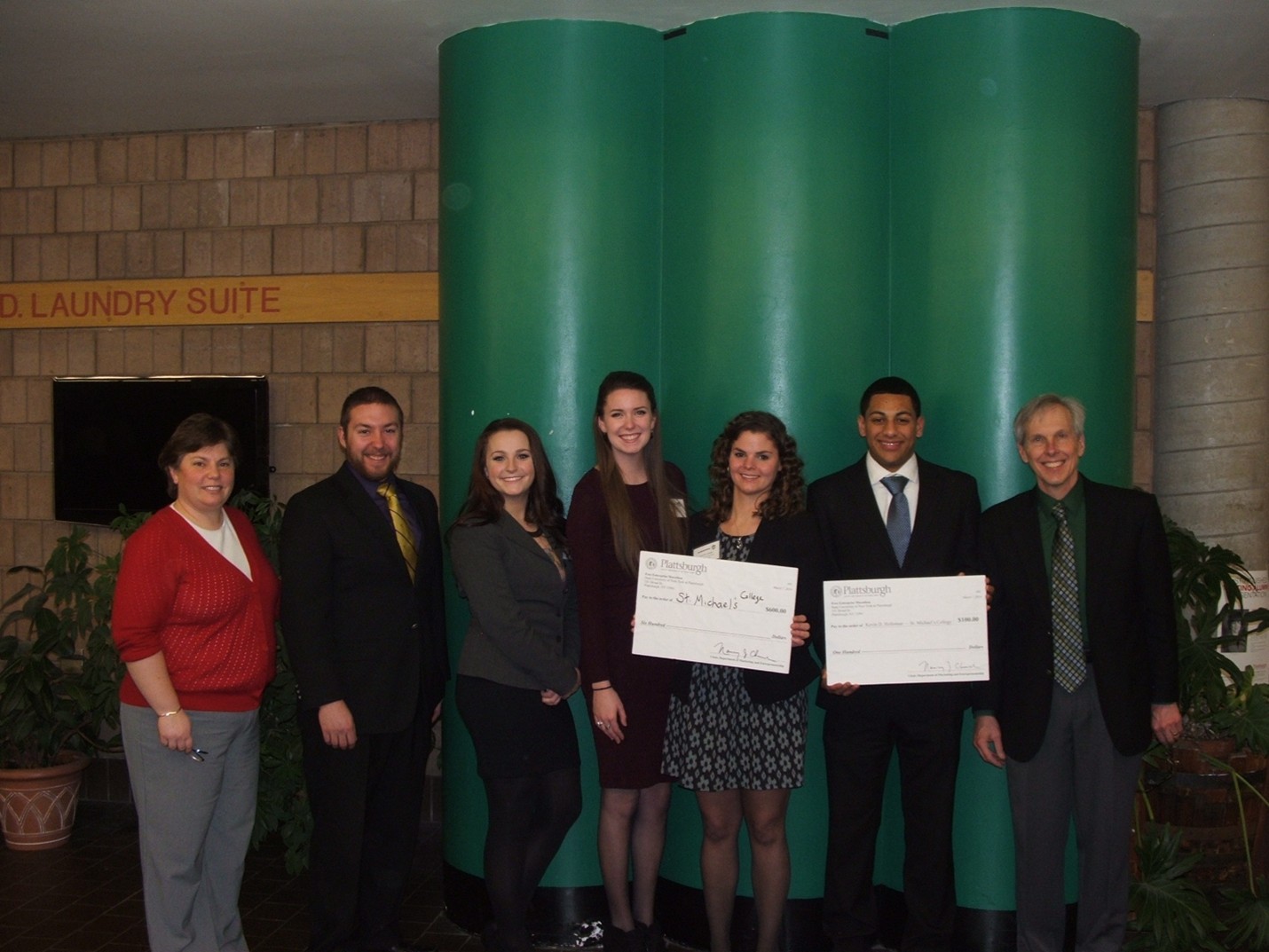 A group of people posing for a photo together holding large checks