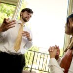 A student wearing a nice shirt and tie speaks to a second person at Saint Michael's College.