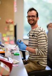 Noah Robinson, Class of 2021, sitting at a lab table holding equipment at Caltech.