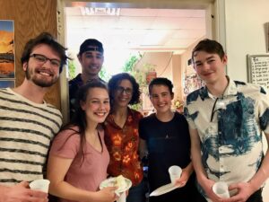 A group of students and one adult pose in the doorway of a classroom.
