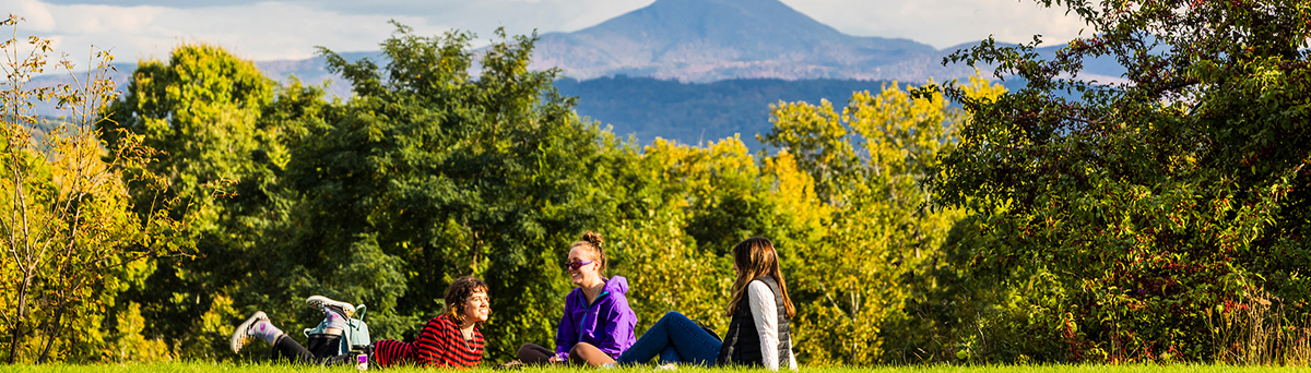 students sit outside, at the view, with mount Mansfield in the background 
