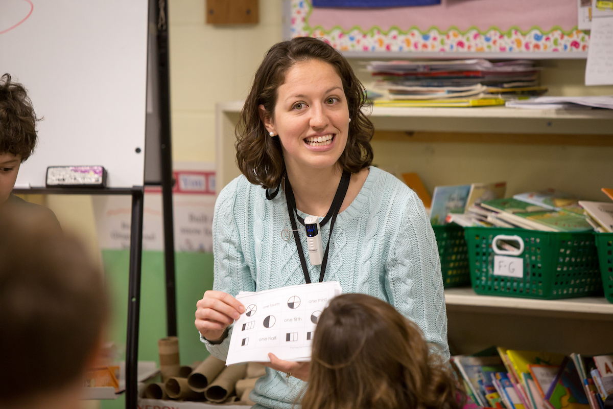 A student teacher holds a card for a class to see