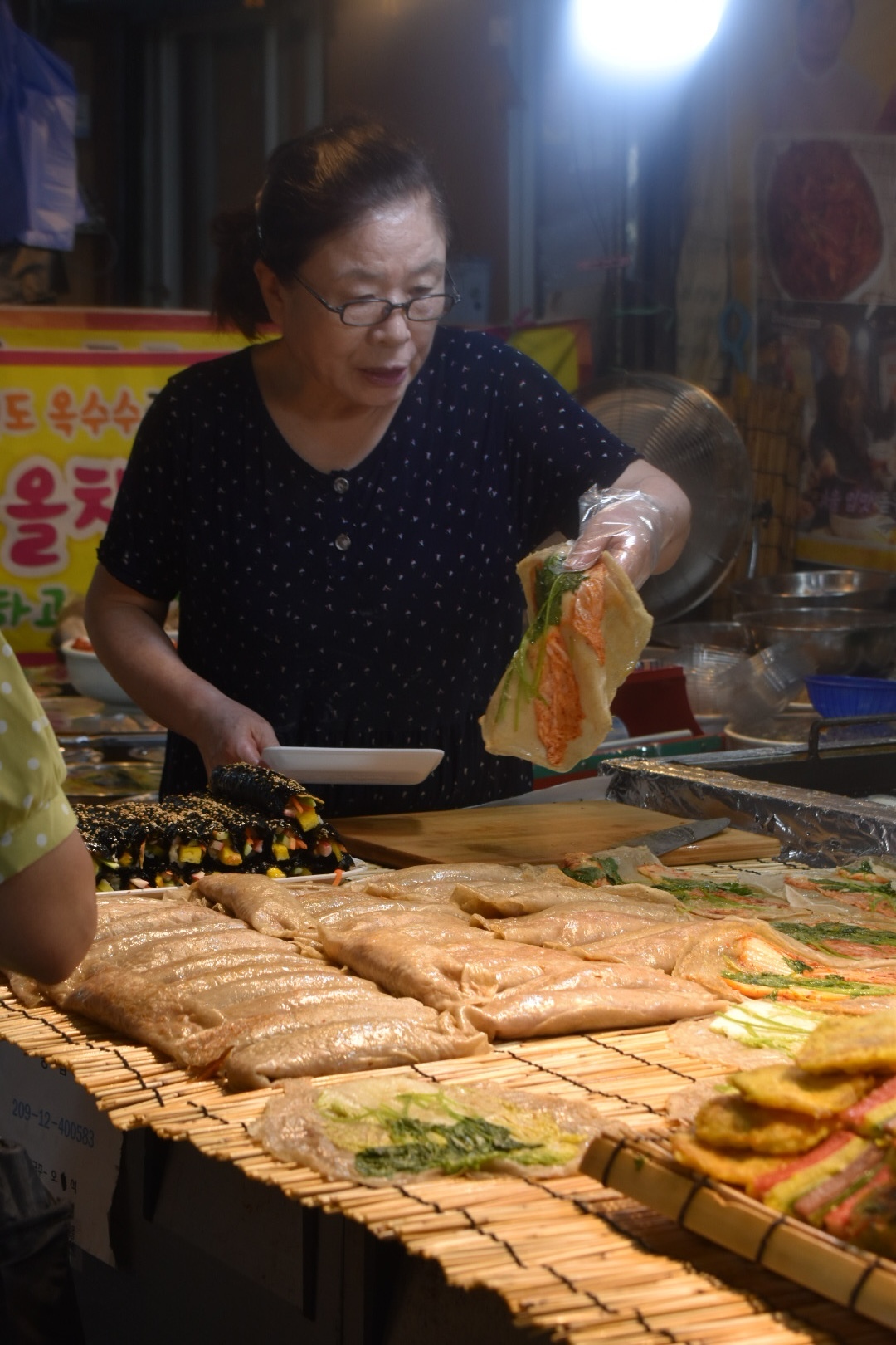 Elderly lady making handmade gimbap at the local market in South Korea