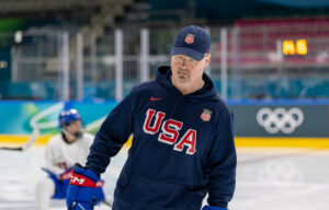 A man skates in the Olympic arena wearing a USA sweatshirt.