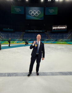 Brent Hill stands in the middle of an Olympics ice rink holding a gold medal