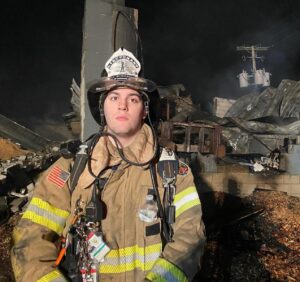 Student firefighter in front of the result of a fire. 