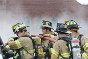 Saint Michael's College firefighters work together to use a fire hose. 