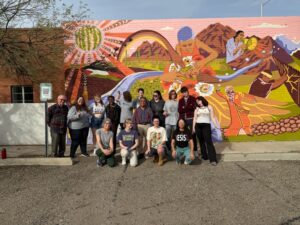 Group photo of Saint Michael's College community members in front of a mural during a 10-day academic study trip to Arizona and Mexico from December 2025-January 2026. 