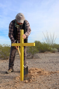 A man places a cross in the ground in Arizona to mark where a migrant died. 