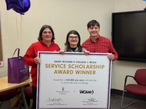 Jenny Blanshine (center) of Champlain Valley Union High School stands with her parents as she is awarded the Saint Michael’s College & WCAX Service Scholarship in March 2026.