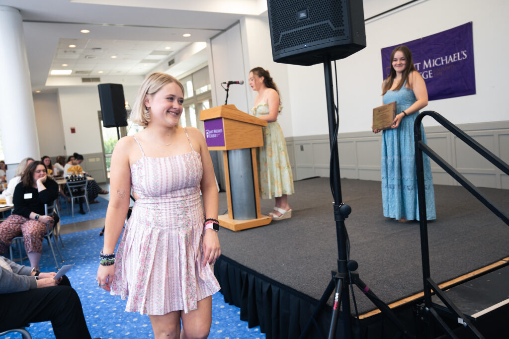 Sophie Burt '26, left, smiles as she walks to the stage to receive a Community Service Award during the Senior Awards Brunch for the Class of 2026 on May 7, 2026. (Photo by Teddy Vretzakis '29)