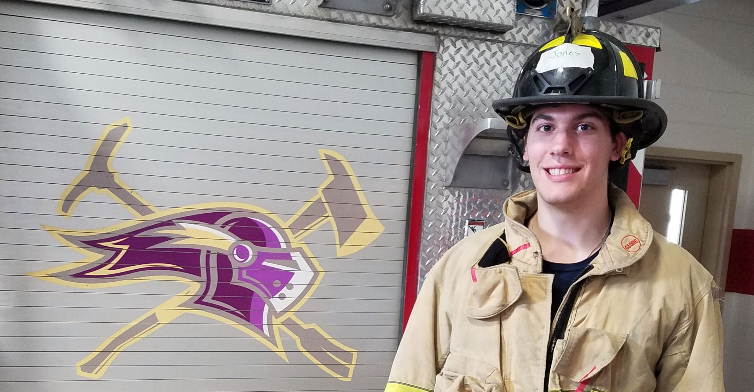Saint Michael's College firefighter poses with fire engine.