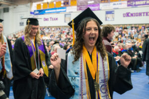 A female graduate reacts with excitement as she walks up to the stage during Commencement. 