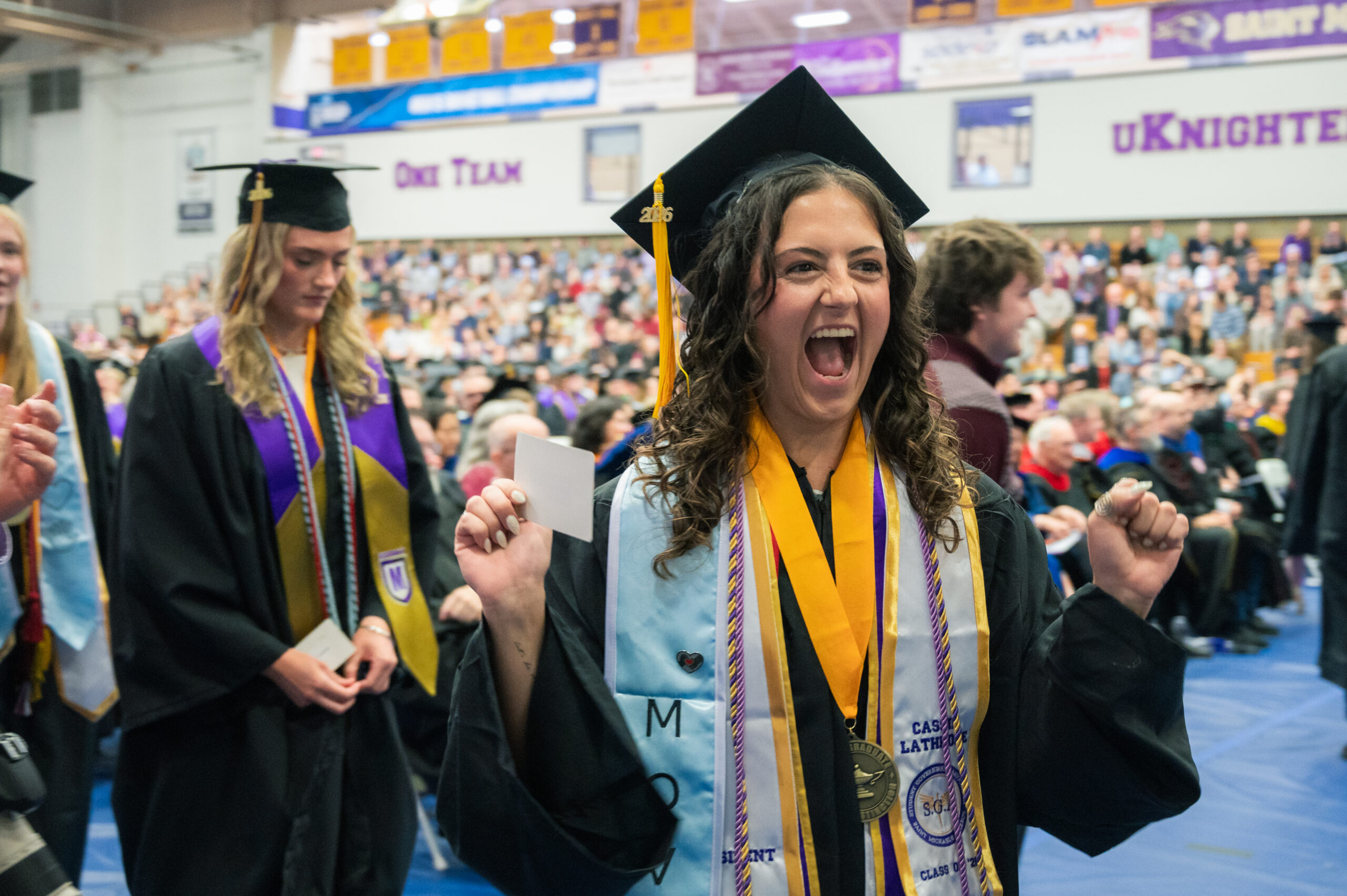A female graduate reacts with excitement as she walks up to the stage during Commencement