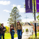 Three students walk away from the cupola on Saint Michael's College campus.