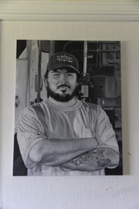 A black and white oil painting of a man with a baseball cap and crossed arms.