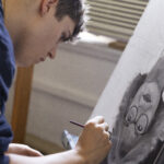 A student paints a black-and-white portrait upside-down, using a technique called "underpainting."