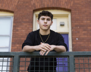 A male student poses in front of a brick building